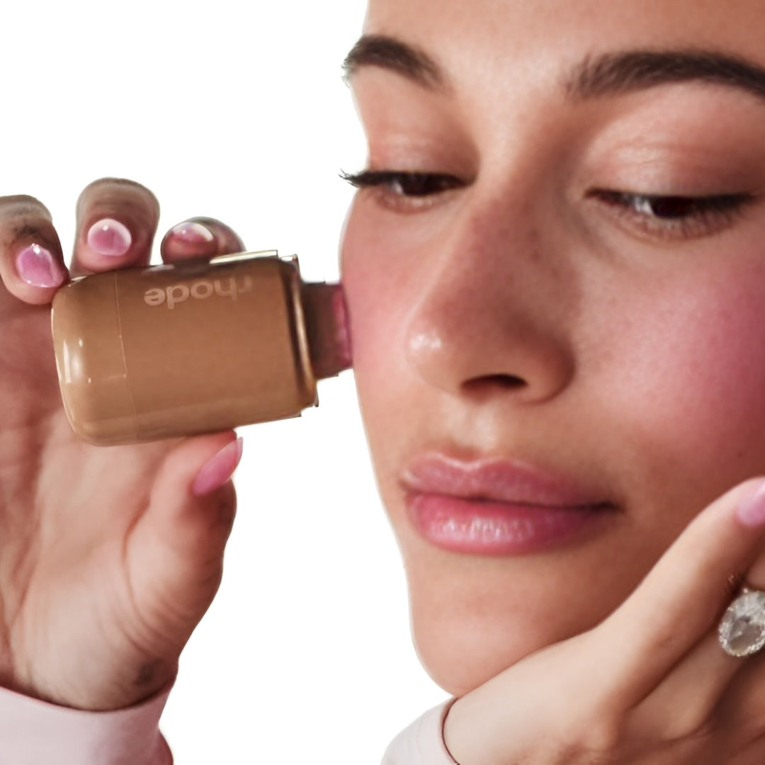Woman applying makeup with a compact mirror on a white background
