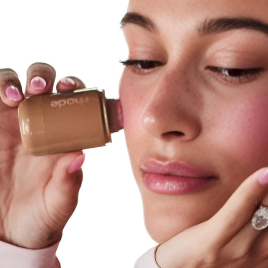 Woman applying makeup with a compact mirror on a white background